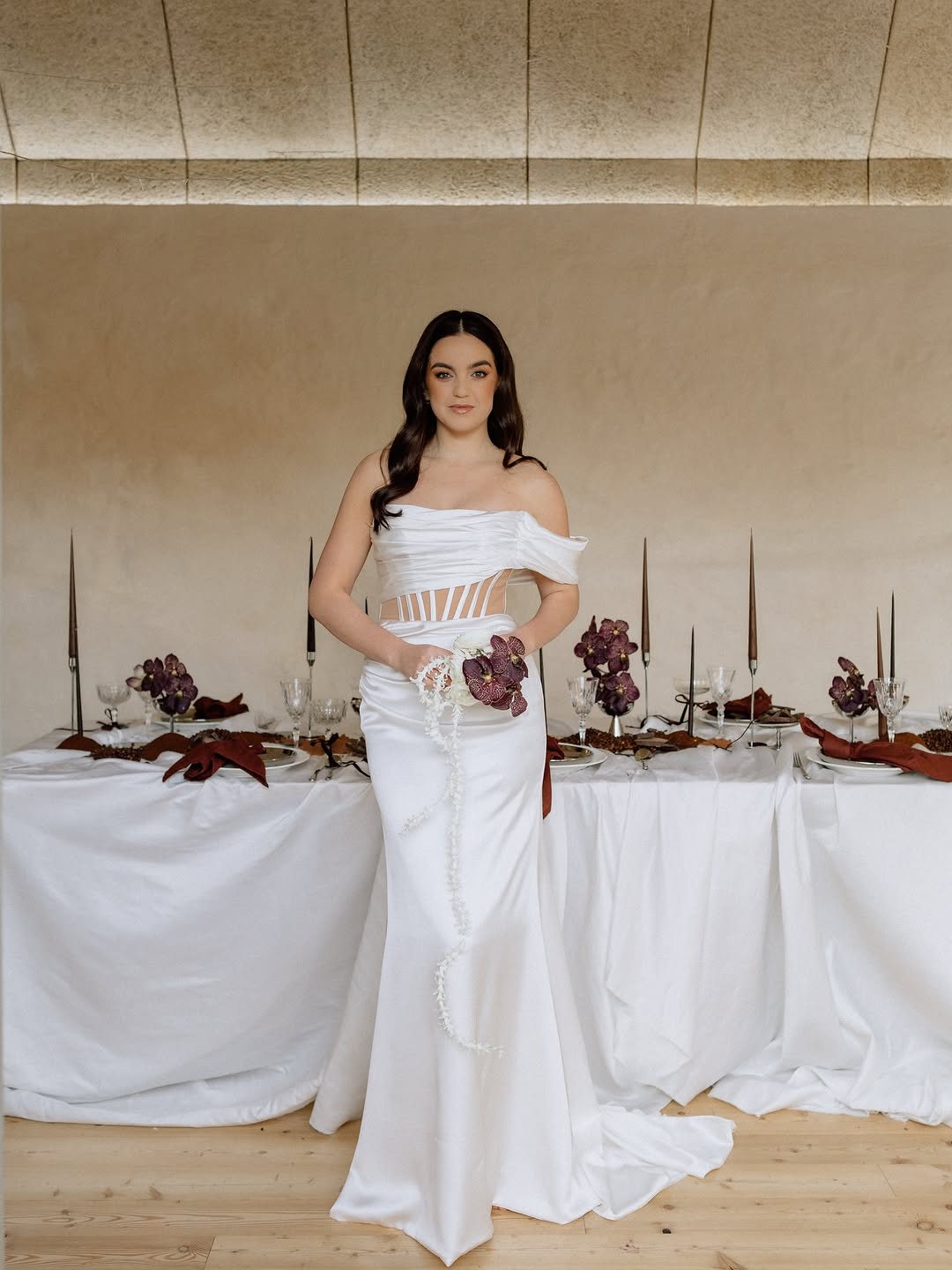 Off-the-shoulder white gown with a full skirt and a narrow beaded waist.