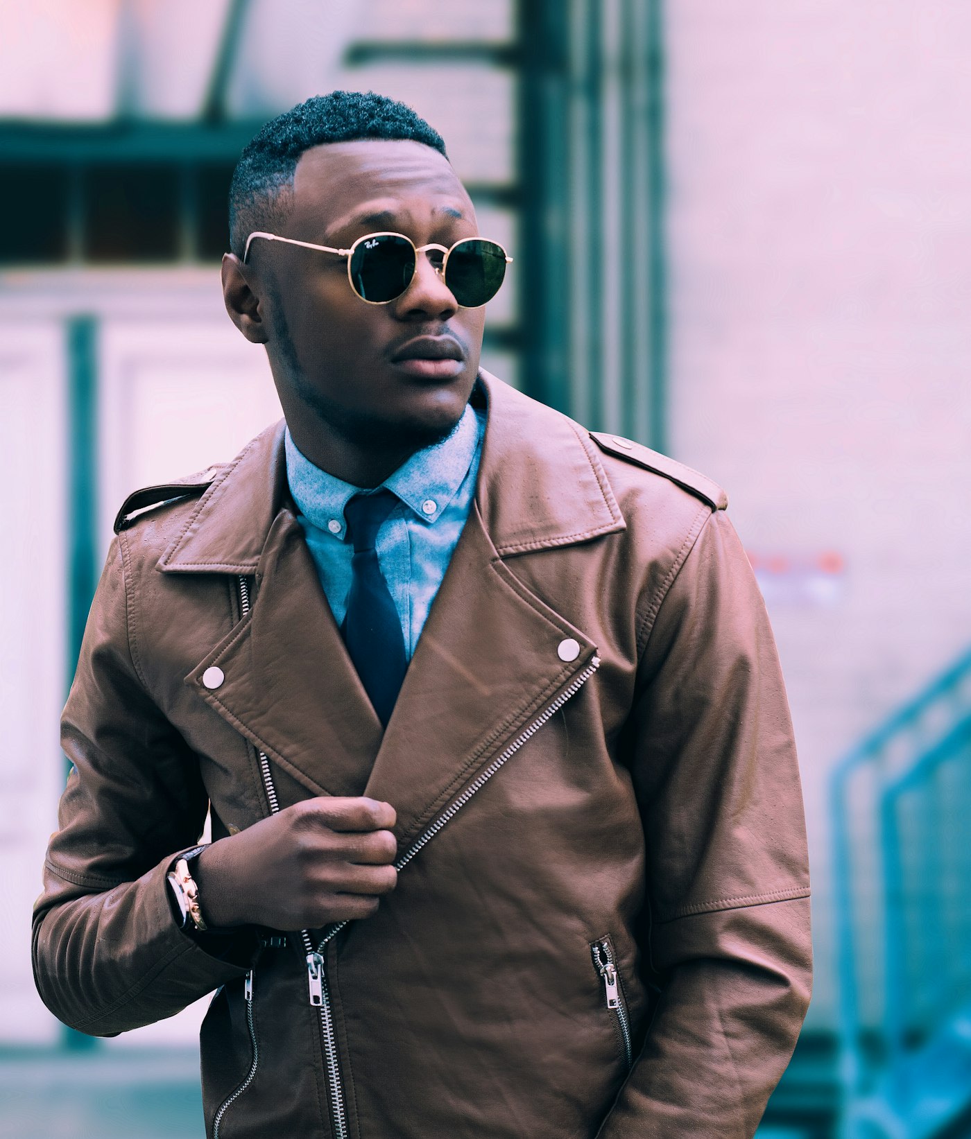 Black blazer and trousers, one hand on the hip, neutral ground.